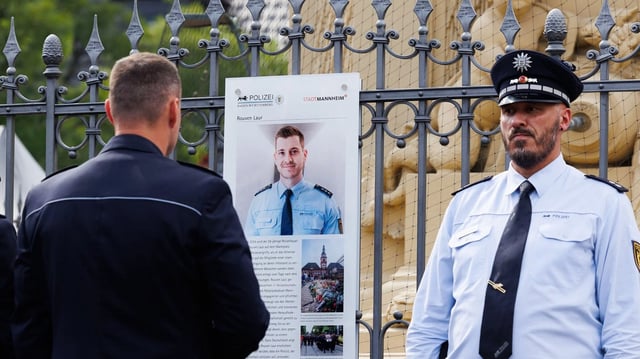 Polizisten stehen vor der Gedenktafel für Rouven Laur