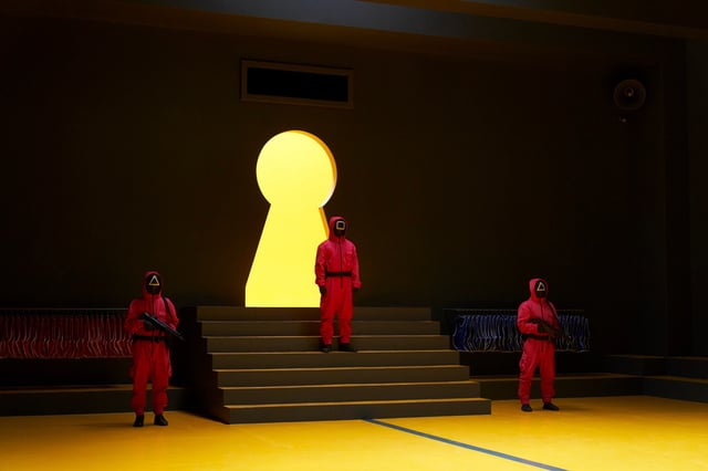 Squid Game guards stand in front of a lit up keyhole in Squid Game season 3