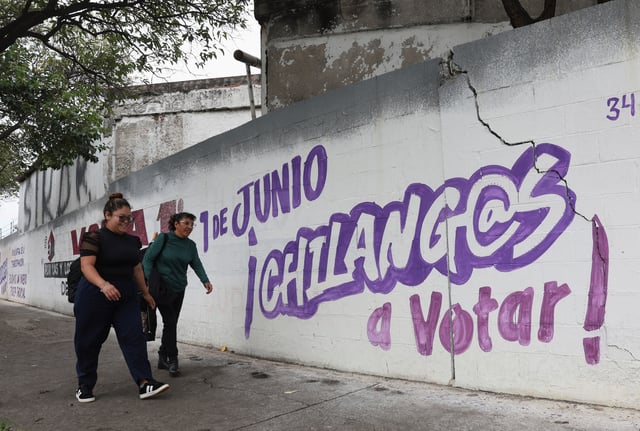 Women walk past electoral propaganda messages painted on a wall encouraging people to vote, ahead of the judicial and magistrate election, in Mexico City, Mexico May 29, 2025. REUTERS/Henry Romero