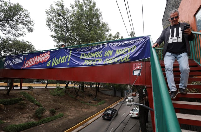 A man walks down stairs as an electoral propaganda banner hangs from a pedestrian bridge encouraging people to vote, ahead of the judicial and magistrate election, in Mexico City, Mexico, May 29, 2025. REUTERS/Henry Romero