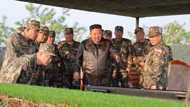 This picture taken on May 29, 2025 shows North Korea's leader Kim Jong Un (C) observing a display by the artillery divisions at an undisclosed location. 