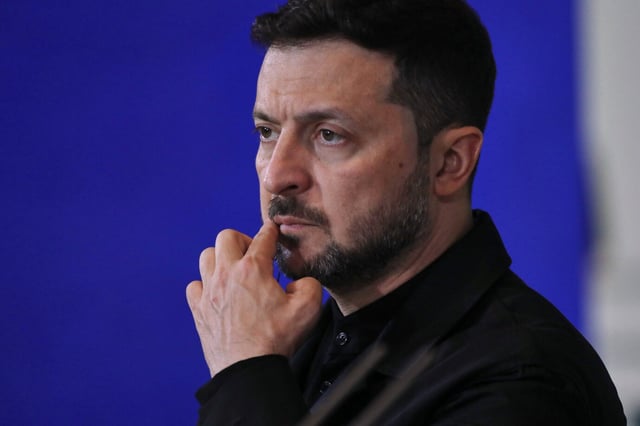 Der ukrainische Präsident Wolodymyr Selenskyj blickt ernst und konzentriert, seine Hand berührt nachdenklich sein Kinn. Er steht vor einem blauen Hintergrund. Ukrainische Drohnen treffen Militärflugplätze in Rußland – weit hinter der Grenze. Dutzende Flugzeuge stehen in Flammen. Derweil bereitet Kiew neue Gespräche mit Moskau vor.