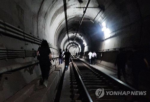 This photo, provided by a Yonhap reader, shows passengers escaping through a tunnel after a man started a fire inside a subway train traveling between the Yeouinaru and Mapo stations on May 31, 2025. (PHOTO NOT FOR SALE) (Yonhap)