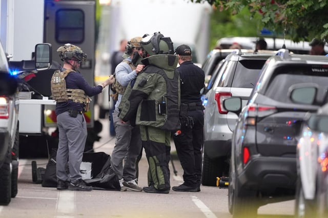 Law enforcement officials put on protective gear to investigate an attack on the Pearl Street Mall, pm Sunday, June 1, 2025, in Boulder, Colo. (AP Photo/David Zalubowski)