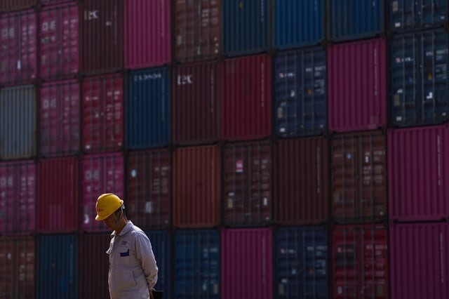 A worker walks by containers at Yangluo Port on the Yangtze River in Wuhan, central China's Hubei Province, on May 23, 2025.