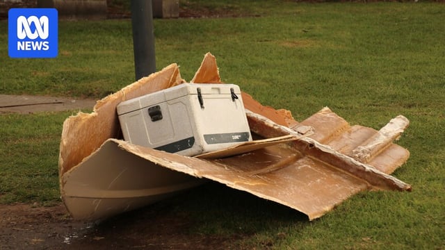 Part of broken boat and a white esky on grass