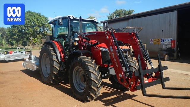 A red tractor sitting on a rural property 