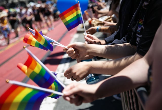 Parade goers hold Pride flags during the annual Pride Parade in San Francisco on June 29, 2024.