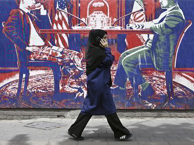 A woman in a hijab walks by an anti-U.S. mural in Tehran on May 3, 2025.
