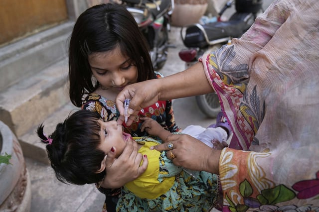 A health worker administers a polio vaccine to a child at a neighbourhood, in Lahore, Pakistan, Monday, May 26, 2025. (AP Photo/K.M. Chaudary)