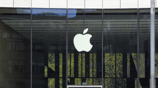 FILE - People sit in front of an Apple Store in Duesseldorf, Germany, Monday, April 7, 2025. (AP Photo/Martin Meissner, File)
