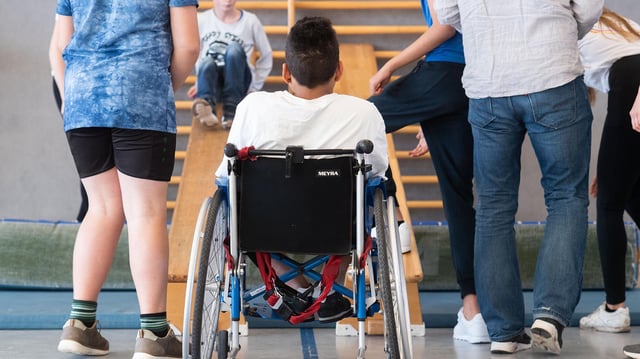 Ein Schüler nimmt im Rollstuhl am Sportunterricht teil.