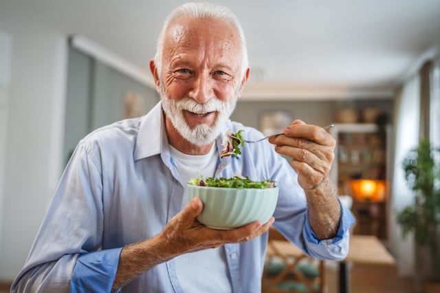 A stock image of a senior man eating a salad.