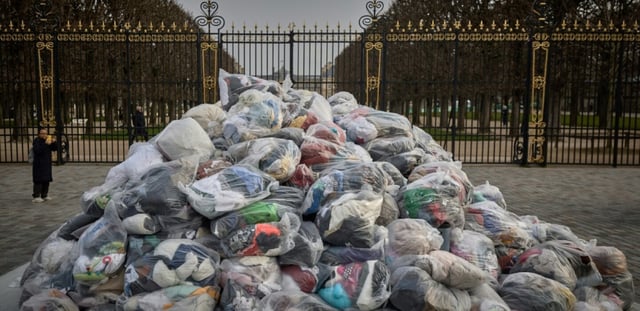 Des sacs de déchets textiles devant la porte du Palais du Luxembourg, où se trouve le Sénat lors d'une manifestation contre la fast-fashion, à Paris, le 14 mars 2025