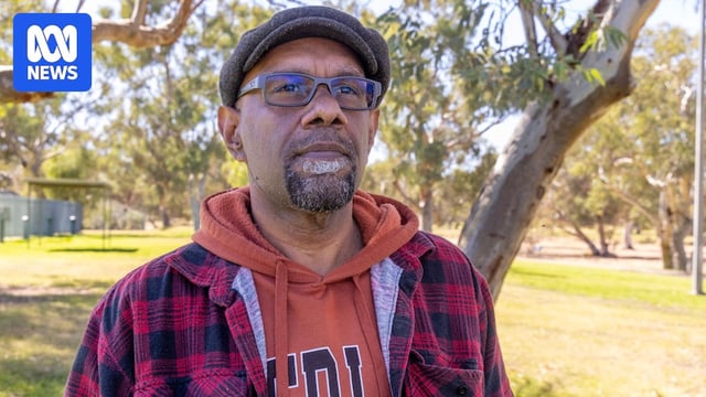 an aboriginal man wearing a hoodie and bowler hat in a park