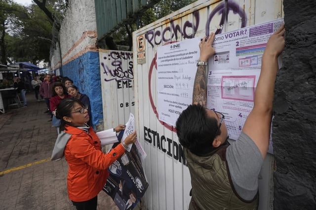 Electoral workers fix signs at a polling station during the country's first judicial elections in Mexico City, June 1, 2025. (AP Photo/Fernando Llano)