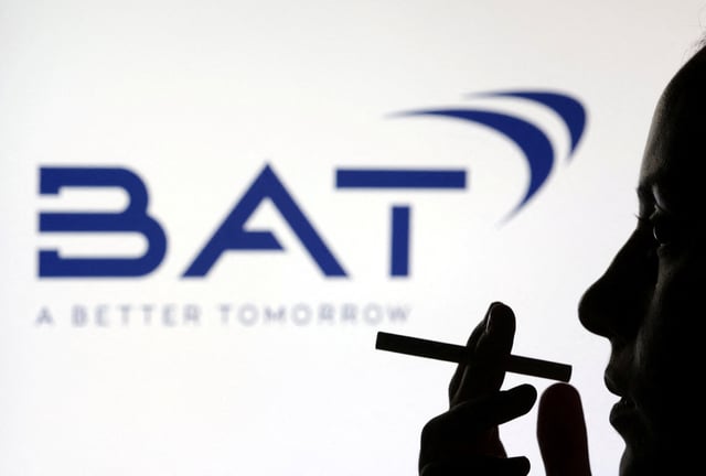 A woman poses with a cigarette in front of BAT (British American Tobacco) logo in this illustration taken July 26, 2022. REUTERS/Dado Ruvic/Illustration/File Photo