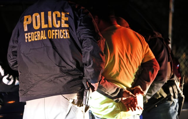 In this Oct. 22, 2018, photo U.S. Immigration and Customs Enforcement agents surround and detain a person during a raid in Richmond, Va. ICE&#39;s enforcement and removal operations, like the five-person field office team outside Richmond, hunt people in the U.S. illegally, some of whom have been here for decades, working and raising families. Carrying out President Donald Trump&#39;s hard-line immigration policies has exposed ICE to unprecedented public scrutiny and criticism, even though officers say they&#39;re doing largely the same job they did before the election, prioritizing criminals. (AP Photo/Steve Helber)