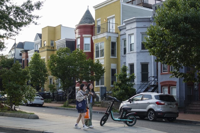 People walk through a neighborhood with row houses on a spring day on May 24, 2025, in Washington, DC.