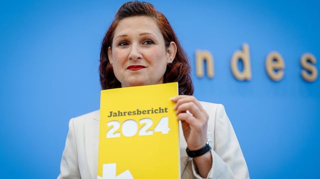 Ferda Ataman hält den Jahresbericht 2024 der Antidiskriminierungsstelle des Bundes in den Händen.