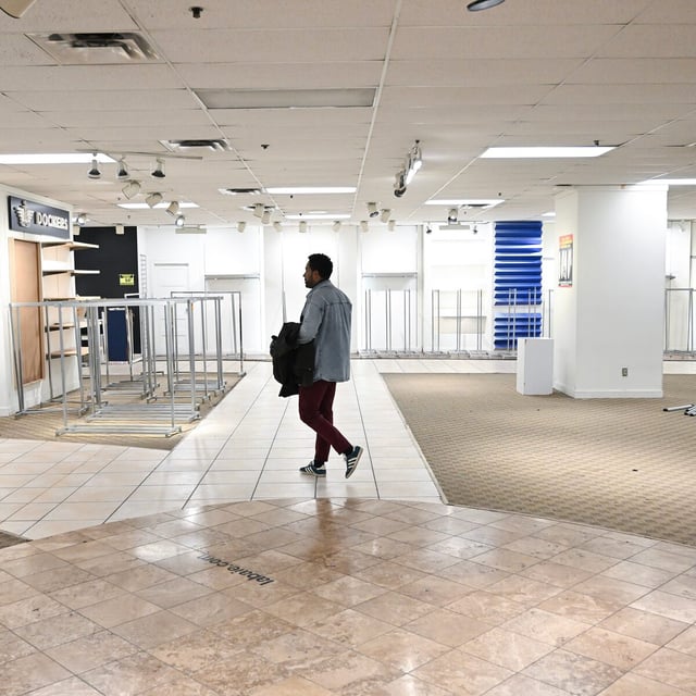 A person walks by empty shelves at a Hudson’s Bay store in Montreal, Sunday, June 1, 2025. It's the final day for the Canadian retailer.  THE CANADIAN PRESS/Graham Hughes
