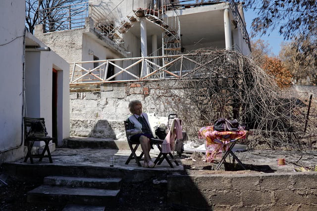 Eleni Anagnostaki, 85, sits in the yard of her destroyed house in the village of Mati, near Athens, Greece, August 22, 2018. Picture taken August 22, 2018. REUTERS/Alkis Konstantinidis/File Photo