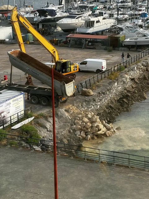 La descarga de rocas de granito sobre la bahía de Baiona para completar el puerto deportivo ha comenzado.