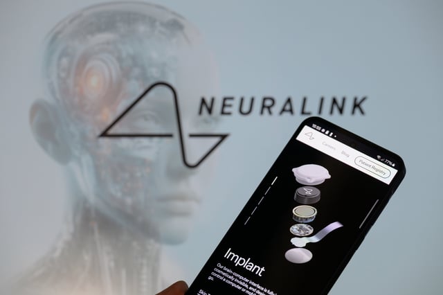 The Neuralink website is displayed on a mobile phone with Neuralink visible in the background in this photo illustration in Brussels, Belgium, on March 9, 2025. (Photo by Jonathan Raa/NurPhoto)