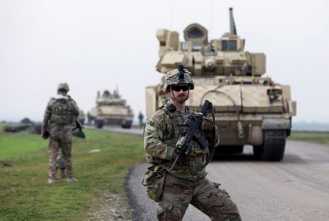 A soldier from the US-led coalition stands guard during a joint U.S.- Kurdish-led Syrian Democratic Forces (SDF) patrol in the countryside of Qamishli in northeastern Syria February 8, 2024. REUTERS/Orhan Qereman/File Photo