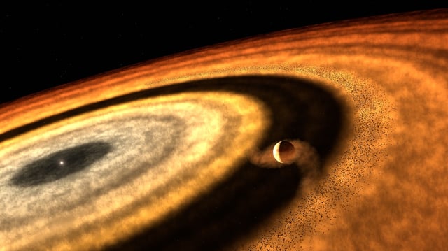 This artistic impression depicts the stage at which WASP-121b accumulated most of its gas, as inferred from the latest results. The illustration suggests that the forming planet had cleared its distant orbit of solid pebbles, which stored water as ice. As a result, the gap prevented additional pebbles from reaching the planet. WASP-121b must have subsequently migrated from the cold, outer regions towards the inner disc, where it now orbits near its star. Credit: T. Müller (MPIA/HdA)