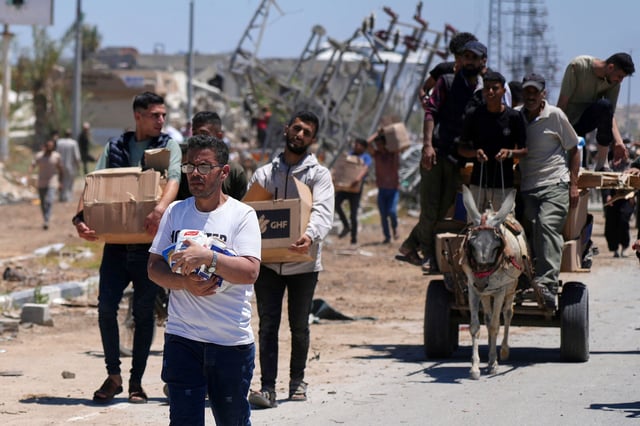 Palestinians carry boxes and bags containing food and humanitarian aid packages delivered by the Gaza Humanitarian Foundation, a US-backed organization approved by Israel, in Khan Younis on May 29.