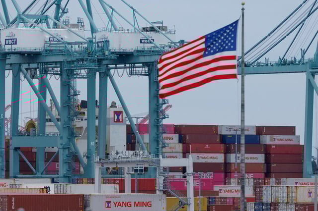 A U.S. flag flutters near shipping containers as a ship is unloaded at the Port of Los Angeles, in San Pedro, California, U.S., May 1, 2025. REUTERS/Mike Blake/File Photo