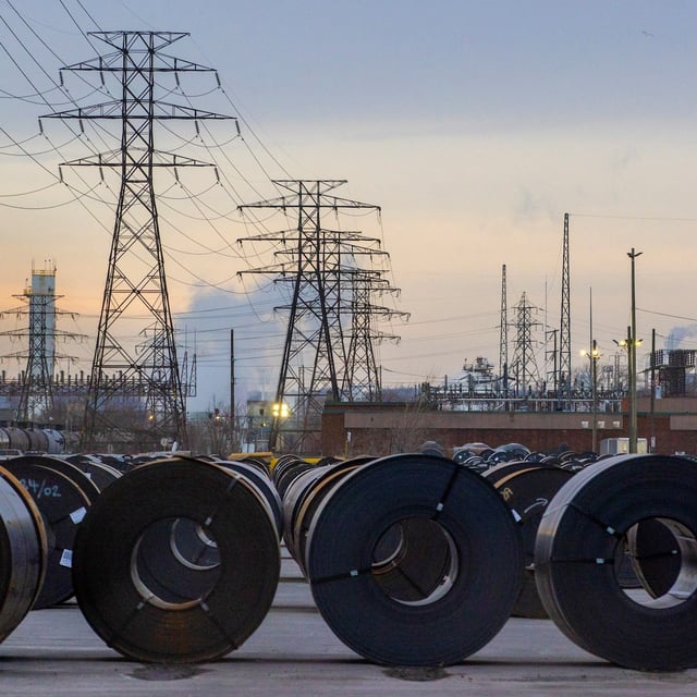 Coils of rolled steel sit in an industrial yard with transmission towers and smokestacks in the background at dusk in Hamilton, Ontario, Canada, January 27, 2025. REUTERS/Carlos Osorio/File Photo