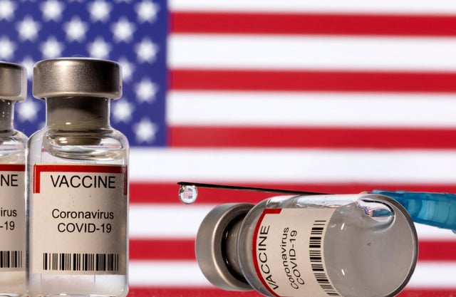 Vials labelled "VACCINE Coronavirus COVID-19" and a syringe are seen in front of a displayed U.S. flag in this illustration taken December 11, 2021. REUTERS/Dado Ruvic/Illustration/File Photo