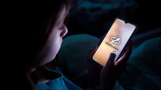 A child using smart phone lying in bed late at night, playing games. Children's screen addiction and parent control concept. Child's room at night. Sensitive content on screen