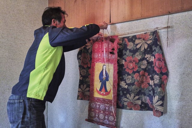 Masatsugu Tanimoto, a farmer and one of the few remaining hidden Christians on Ikitsuki Island, hangs a scroll of the Virgin Mary and Jesus once secretly worshipped at his home in Ikitsuki Island in Hirado, southern Japan, Sunday, April 27, 2025. (AP Photo/Eugene Hoshiko)