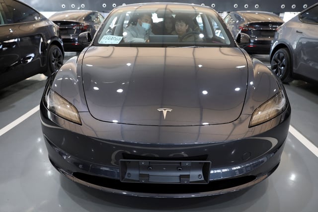 Customers sit in a Tesla Model Y electric vehicle (EV) at the carmaker's delivery centre in Beijing, China January 8, 2025. REUTERS/Florence Lo/ File Photo