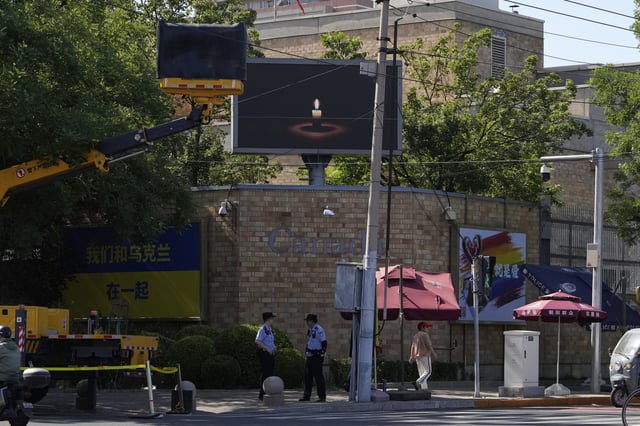 A boom lift partially blocks the view of a screen depicting a lit candle at the Canadian Embassy on the anniversary of China's bloody 1989 crackdown on pro-democracy protests in Beijing, Wednesday, June 4, 2025. (AP Photo/Ng Han Guan)