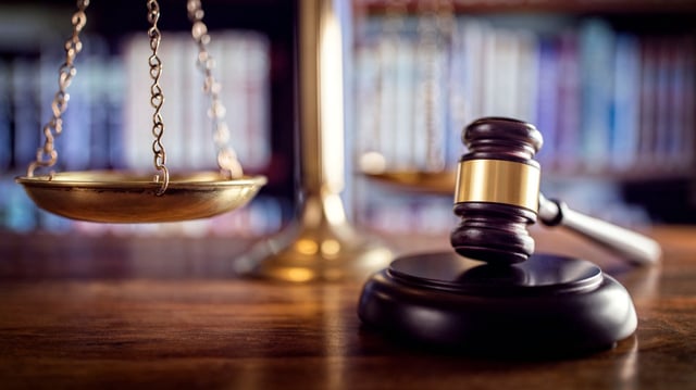Judge gavel, scales of justice and law books in court.