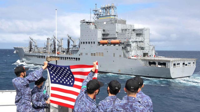 Besatzungsmitglieder des japanischen Lenkwaffenzerstörers JS Shimakaze halten eine US-Flagge in Richtung des US-amerikanischen Öltankers USNS Harvey Milk.