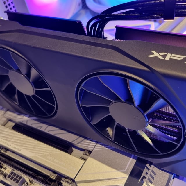The XFX Swift AMD Radeon RX 9060 XT in a benchmarking PC, lit up with RGB