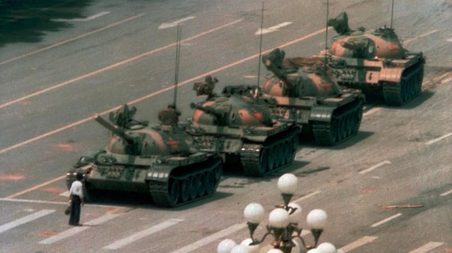 Ein Mann stellt sich einem Konvoi von Panzern entgegen.