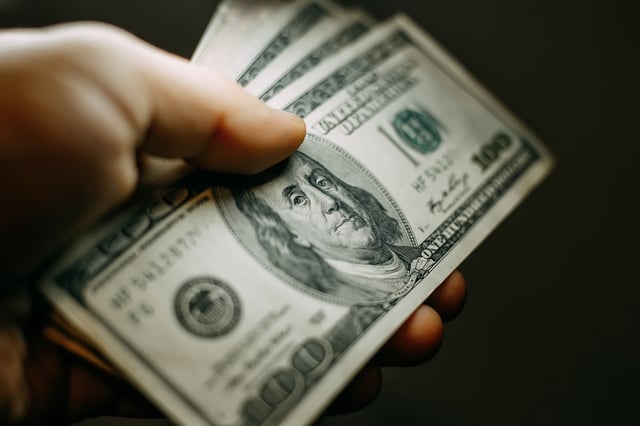 Stock image/file photo: A person holding several $100 bills.