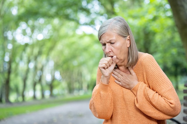 A stock image of a woman coughing.