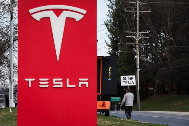 Protestors gather in front of a Tesla dealership in Owings Mills, Md., on Saturday, March 29, 2025. (Wesley Lapointe/The Baltimore Banner via AP)