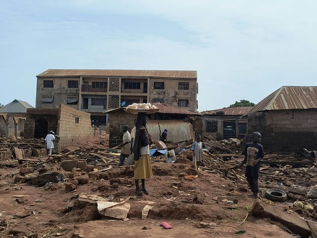 A woman stands next to debris from damaged buildings in Mokwa after the Nigerian town was hit by torrential rains, with the resulting flash flooding displacing more than 3,000 people