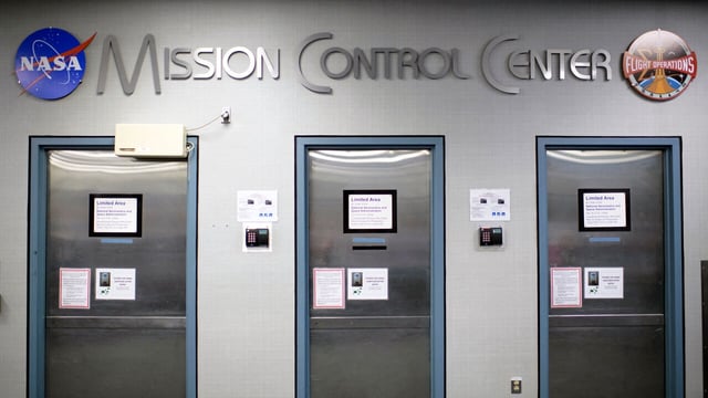 A sign reading "Mission Control Center" is displayed above doorways at the Johnson Space Center's Mission Control Center in Houston