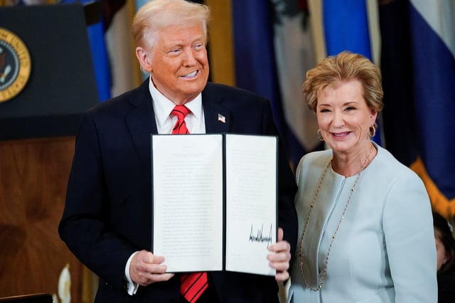 U.S. President Donald Trump reacts next to  U.S. Secretary of Education Linda McMahon as he shows the executive order to shut down the Department of Education, in the East Room at the White House in Washington, D.C., U.S., March 20, 2025. REUTERS/Nathan Howard/File Photo
