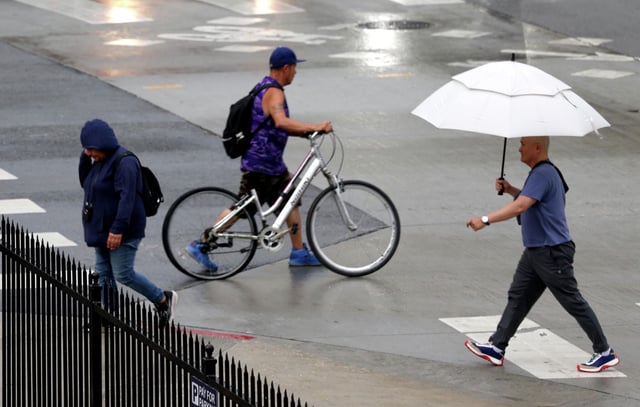 Pedestrians make their way through an afternoon rain in downtown Los Angeles on Tuesday. Southern California was hit by rare June rainfall, which broke a daily and monthly precipitation records in the desert city of Needles (San Bernardino County).