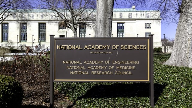 Image of a science in front of a marble building, declaring that the building hosts the National Academies of Science.